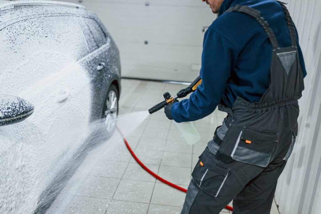 male-worker-in-uniform-washing-new-modern-car-that-KX9YT5C-scaled